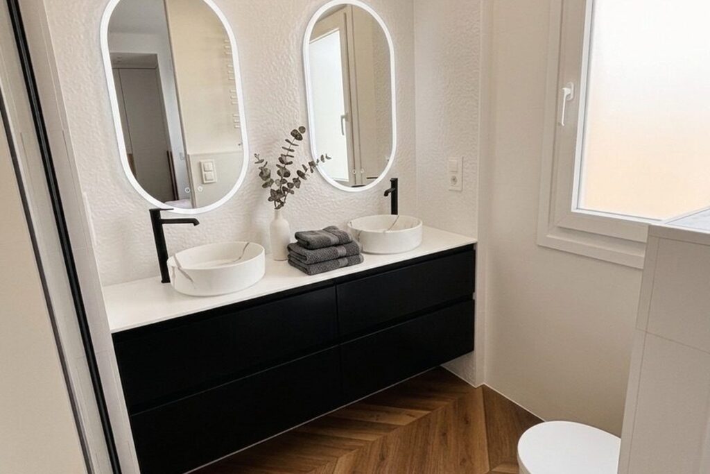 Bano doble con espejos LED y mueble negro suspendido en reforma integral Zaragoza