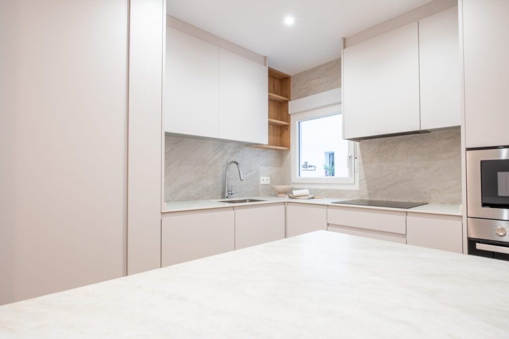 Cocina reformada con isla y muebles en tono arena